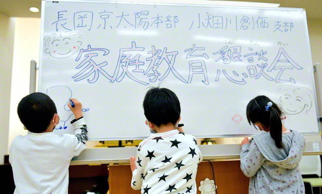 家庭教育懇談会の会場に置かれたホワイトボードに、自由に絵を描く子どもたち(今月4日、長岡京文化会館で)