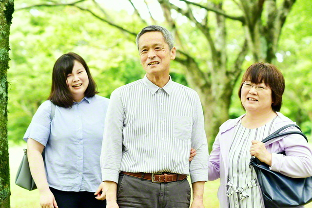 「腕を組むのなんて何年ぶりかな(笑い)。これも、病気になったおかげ」と照れ笑いする前田さん㊥を妻・英巳子さん㊨と長女・由美子さんが囲む