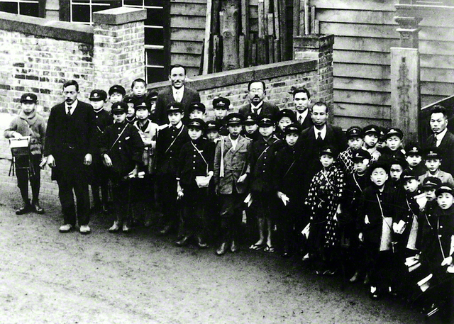 初代会長の牧口先生(左から2人目)が、校長を務めていた東京・白金小学校前で児童たちと。牧口先生は「子どもの幸福」を第一とする人間教育を提唱した