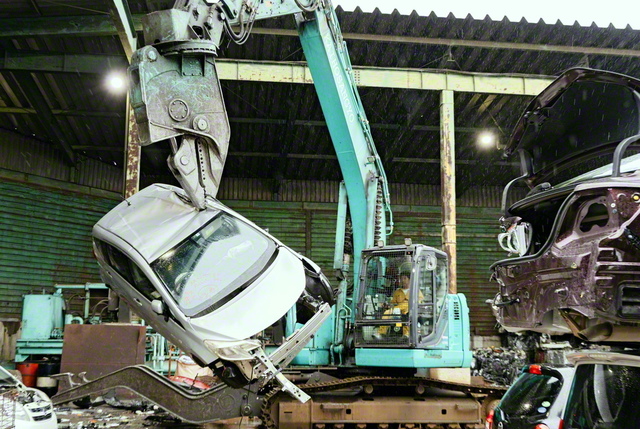 工場内にある巨大な重機を使い、自動車の解体作業が行われる