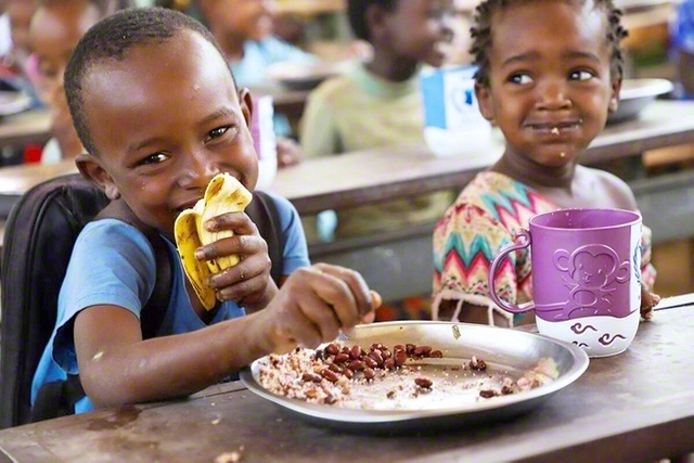 WFPの支援で提供される学校給食を口にするエチオピアの子どもたち（2023年）　©WFP/Michael　Tewelde