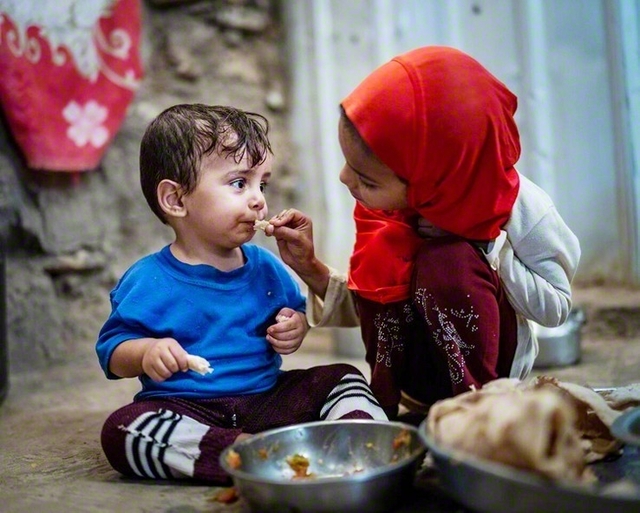 イエメンの難民キャンプで、姉が幼い弟に食事を与える（2023年）　©WFP/Sayed　Asif　Mahmud