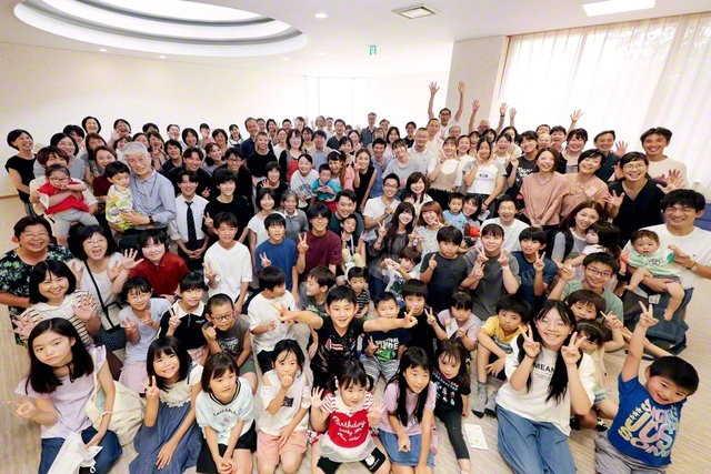 「立川池田区サマーチャレンジ」に集った未来部員と保護者、未来部担当者らが記念のカメラに（立川文化会館で）。参加した小具遙菜さん（高校2年）は「サマチャレの魅力は、創価家族の仲が深まること」と笑顔で