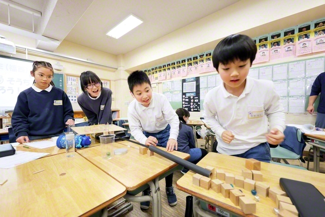 東京創価小学校の取り組み「asobiゼミナール」の一こま。ビー玉はゴールにたどり着くかな？　ワクワク！――自分たちで作った「からくり装置」を見つめる児童たち