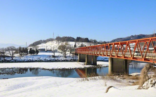 千曲川に架かる赤い古牧橋。白雪とのコントラストが鮮やかに（長野県飯山市から中野市側を撮影）＝長野・小林充通信員