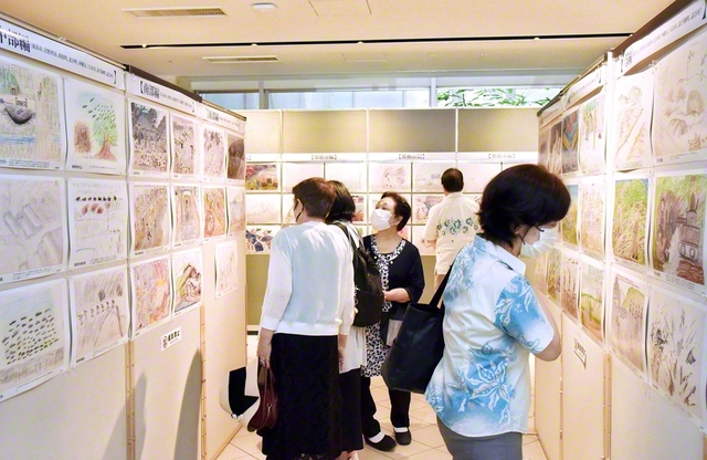 「沖縄戦の絵」展。本島南部の絵には海岸まで住民が追い詰められたシーンがあり、北部の絵には山中を逃げる場面があるなど地域ごとに特徴がある。来場者は惨状が描かれた一枚一枚を真剣に見入っていた（琉球新報本社で）