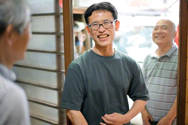 昨年6月から地元・西陵中央地区で地区部長を務める畠中聖さん㊥。かつて外出も困難だったのがうそのように、友のもとへ足を運び、語らいに花を咲かせる。その胸には、苦境を越えて得た希望が（鹿児島市内で）