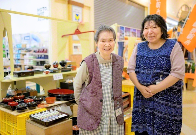 市内のスーパーで開かれる出張朝市に立つ福岡さん㊧と長女・直子さん