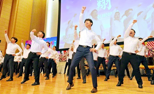 韓国全土の圏男子部長120人が、学会歌「紅の歌」の指揮を力強く。渾身の姿に決意の波動が広がった（池田記念講堂で）