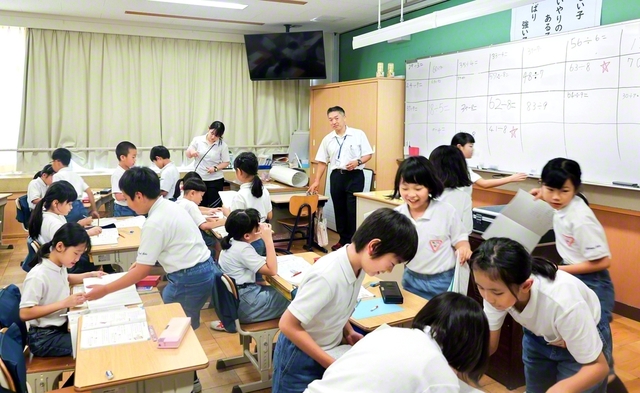 算数の授業の終盤。田代光章教諭（中央の男性）と春増利子教諭（その左の女性）が児童を見守り、関わる