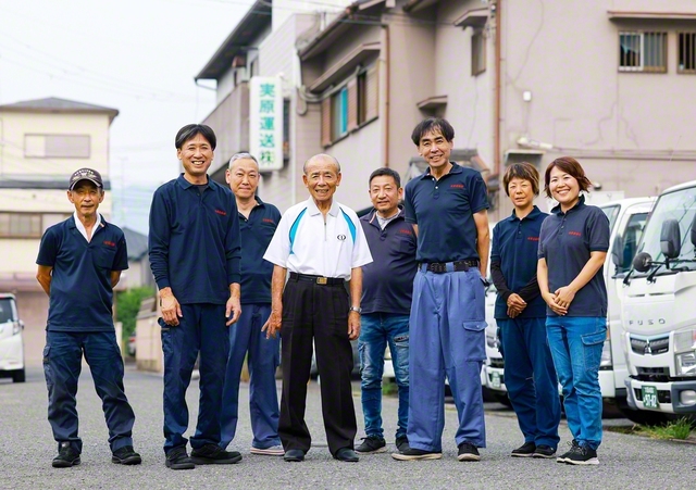 「社員は宝。皆の健康と幸せを毎日祈っています」と実原さん（前列中央）。長男・清孝さん（右から3人目）と次男・隆也さん（左から2人目）、清孝さんの妻・亜希さん（右端）も会社を支える