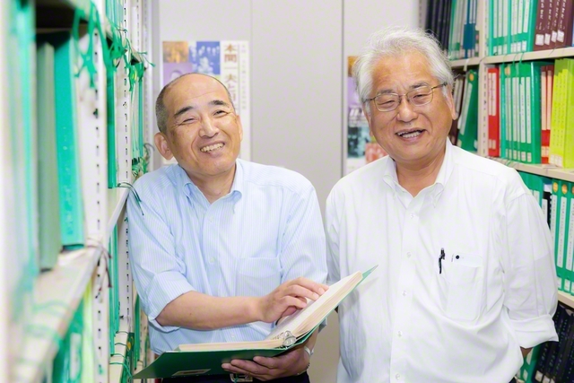 書庫内で、点字本を開く立花館長㊧と伊藤本部長