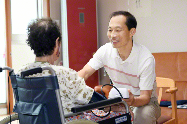 訪問した利用者宅で介護サービスを行う張圭龍さん㊨