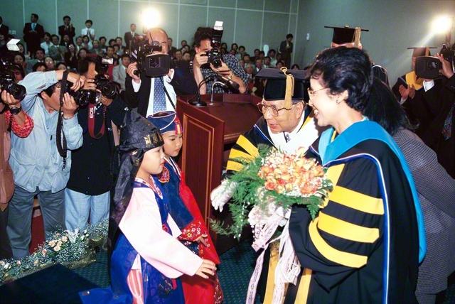 韓国・済州大学から池田先生への「名誉文学博士号」授与式。席上、民族衣装に身を包んだ子どもたちからの花束に、先生ご夫妻が心からの感謝を（1999年5月17日、同大学で）