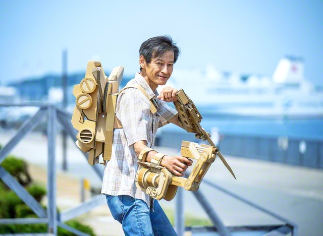 作品を身にまとった山口さんは、カメラを向けるより先に、決めポーズ。「この段ボールの断面がいいでしょ。色を塗っちゃあ、もったいないよね。ここんところを押せば、ほら変形もするし……」。話し出したら止まらない