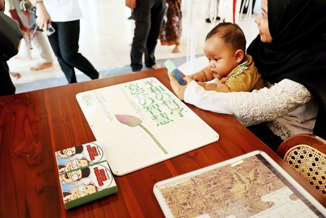 対談集の表紙をモチーフに制作されたパズルで遊ぶ親子