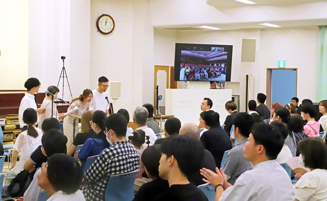 広布前進の誓いを新たにする兵庫・西宮総県とマレーシアの集い。マレーシアのチュー・オード・レイさんが信仰体験を力強く。“労苦こそ人生の宝”との池田先生の指針を胸に、起業したデザイン会社で信頼を広げ、職場の同僚が御本尊を受持した喜びを語った（西宮平和講堂で）