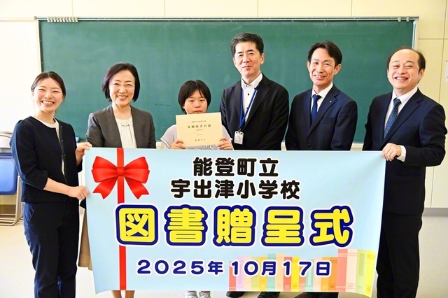 宇出津小学校での贈呈式。表川石川総県長があいさつし、野畠同女性部長が代表の児童に目録と図書を手渡した