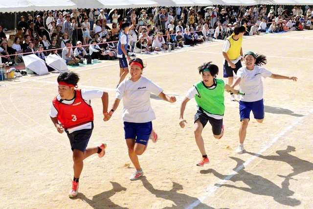 クラス対抗リレーで、チームメートに必死にバトンを渡す学園生（同）