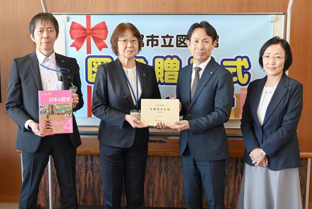 七尾市立図書館への図書贈呈式。酒井館長（左端）、八崎教育長（左から2人目）らが記念のカメラに