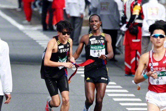 3区・ムチーニ選手㊨から4区・織橋選手へタスキリレー（第3中継所・霞ケ浦緑地前で）