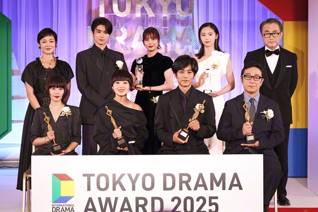 受賞者と司会者が記念のカメラに