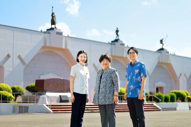 沖縄研修道場の「世界平和の碑」の前で記念のカメラに（左から渡名喜さん、當山さん、山口さん）