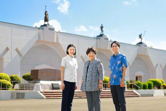 沖縄研修道場の「世界平和の碑」の前で記念のカメラに（左から渡名喜さん、當山さん、山口さん）