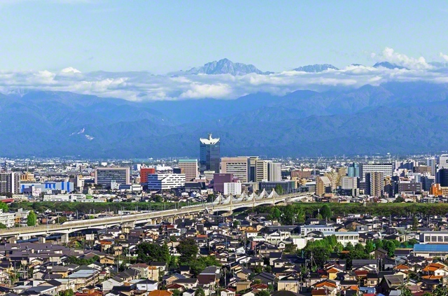 市の西部にある呉羽山公園展望台から望む富山市中心部。北陸新幹線が通り、奥には立山連峰が見える