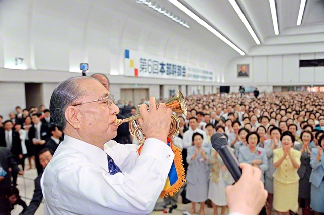 九州総会の意義をとどめた本部幹部会。九州青年部から届いた自動演奏の「完勝ラッパ」を手に、池田先生が友の待つ会場へ（2001年5月21日、東京戸田記念講堂で）