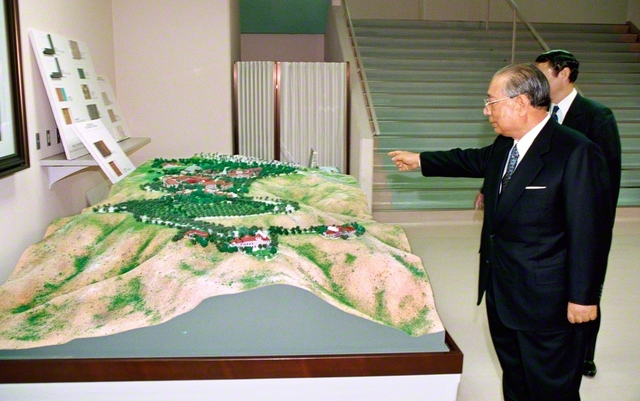 アメリカ創価大学のオレンジ郡キャンパスの建設が進む中、完成模型を見つめる池田先生（1998年3月、八王子市の創価大学で）。この建設が決定した直後（95年4月）に池田先生は、「見渡す限り、緑の丘陵がなだらかに続く。一つ山を越えると、青き太平洋が雄大に広がる」「この理想的な天地に、大きく夢を広げながら、荘厳なる『教育の城』を建設してまいりたい」と語った