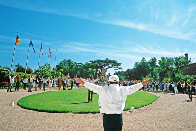 抜けるような青空の下、イギリスSGIのタプロー・コート総合文化センターで、同志と体操を行う池田先生。滞在中に開かれた青年部総会で先生は“全員が社会の勝利者に”とエールを送った（1991年6月）