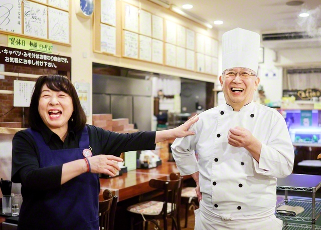 古我さん㊨の料理と妻・秋美さんの接客で、店内はいつもにぎやか。30年前に独立する時、子どもたちが店名や店のキャラクターを考えてくれた