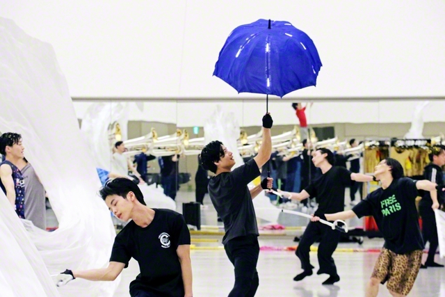 ショーの中では試練の風雨を「傘」で耐え忍ぶ様子を表現。プロップ（舞台道具）を手作りで作製している製作部メンバーの陰の努力が光っている