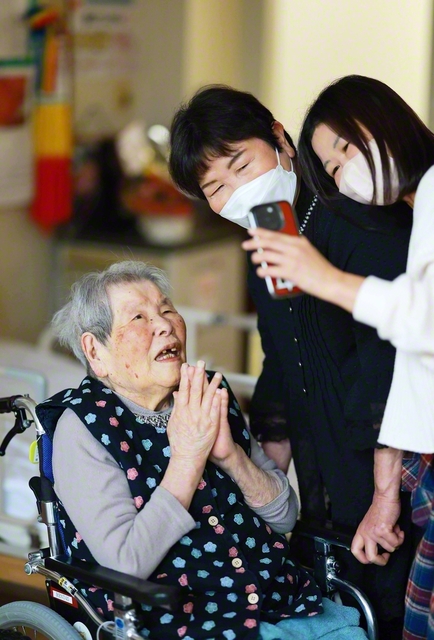 「題目第一でいこうでー」。テレビ電話をするウメさん㊧。長女の松枝さん㊥と孫の宏美さんが見守る