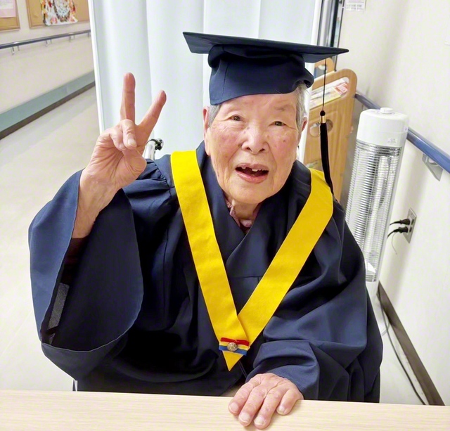 ガウン姿でピースするウメさん