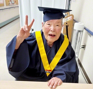 ガウン姿でピースするウメさん