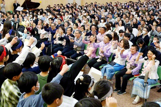 歓迎の歌声を届けた少年少女部の「水魚合唱団」。大古明美さんが世界での奮闘を報告した（東京国際池田記念講堂で）