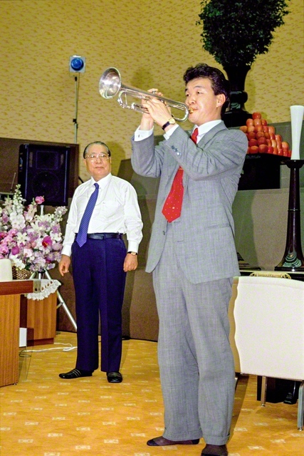 トランペッターの大野俊三さんが「オーバー・ザ・レインボー」の演奏を披露。交通事故の試練を乗り越えた弟子の雄姿を、池田先生がそばで見守った（1991年3月12日、中部池田記念講堂で）