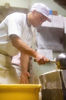 出来たての熱々の豆腐を木枠に流し込む野仲さん。おいしい豆腐を作りたい、と一心に