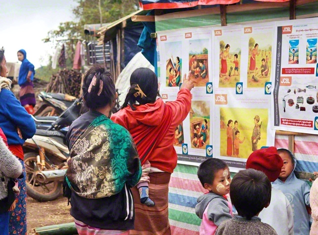地雷の危険回避教育のポスターを見る親子（ミャンマー・カヤー州で、筆者提供）