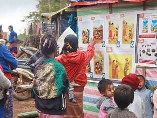 地雷の危険回避教育のポスターを見る親子（ミャンマー・カヤ-州で、筆者提供）