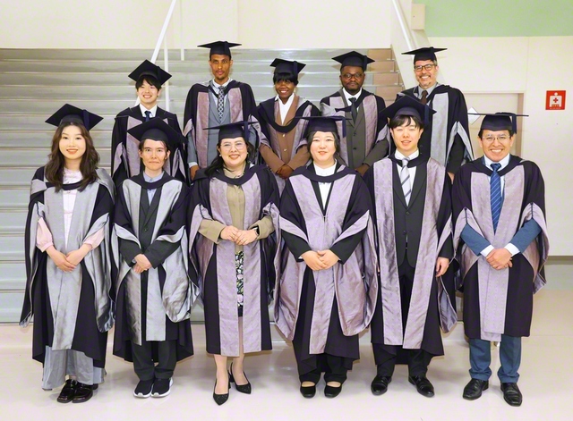 博士号取得者の代表が記念のカメラに（創大池田記念講堂で）