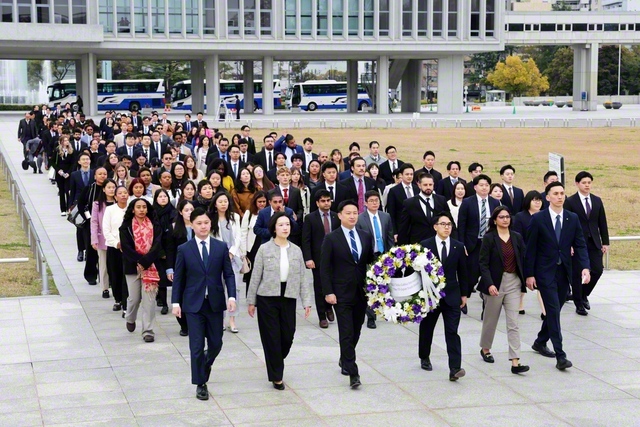 アメリカ青年部、日本の青年世代の代表が原爆死没者慰霊碑に献花。題目三唱の時刻は、原爆投下と同じ8時15分。メンバーが顔を上げると「平和の時計塔」の鐘が鳴り響いた（広島市内で）