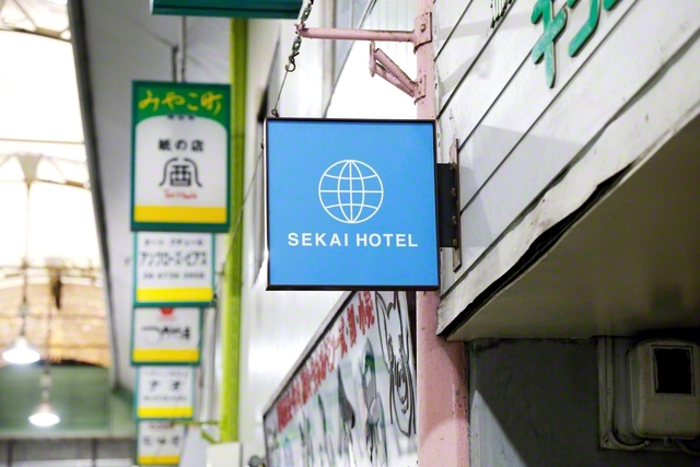ホテルのフロントに掲げられた「SEKAI　HOTEL」の突き出し看板