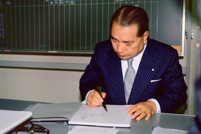 書籍に激励の言葉をしたためる池田先生。“この一瞬があれば”と、寸暇を惜しんで友に勇気を送る（1980年10月26日、千葉文化会館で）