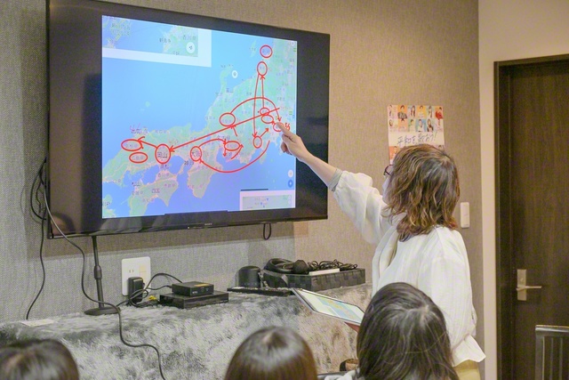 オランダ塾での一こま。ある章の中で山本伸一が滞在した都道府県と日付を示した日本地図を画面に映し出しながら解説