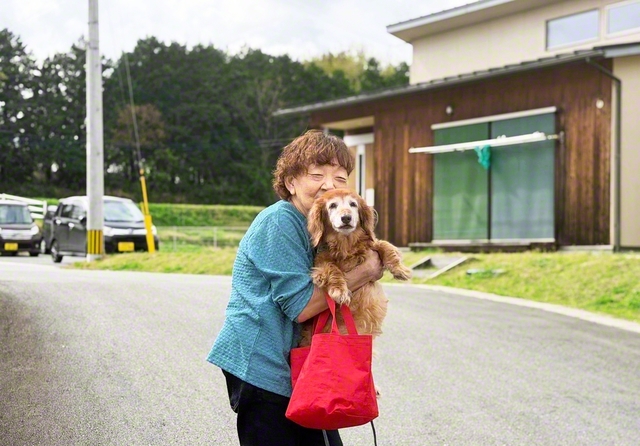 西原村の災害公営住宅に暮らす楠フミヨさん。地震後も苦楽を共にしてきた家族同然の愛犬・セブンと笑顔で