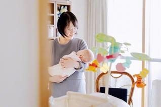 日だまりの部屋で、娘のひよりちゃんを優しく抱き上げる吉澤さん。苦難も涙も、「全部に感謝です」とほほ笑む