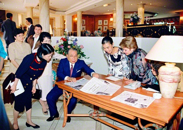 ヴァイツゼッカー大統領との会談を伝える聖教新聞の記事を見ながら、SGIメンバーを励ます池田先生。その誠実な振る舞いは、誰が相手でも変わらない（1991年6月、ドイツ・ボンで）